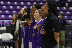 Members of the womens basketball team place their hand over their heart as the National Anthem is sang. (Cydnee Green / The Signpost)