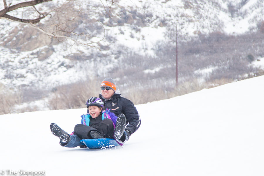 Rusty Conway and daughter Kyann Conway, 7, sled at Mt. Ogden Park. (Christina Huerta / The Signpost)