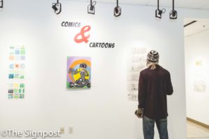 Sam Jeffery, 18, reads a comic at the reception of the Comics and Cartoons exhibit in the Shepherd Union Gallery.(Christina Huerta/The Signpost)