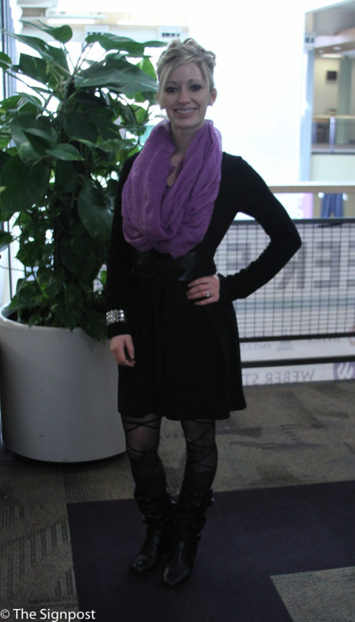 Amber Reeves, a Freshman taking generals is wearing a black dress with black tights and boots and a purple scarf.  (Ariana Berkemeier / The Signpost)