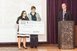 Zions Bank Region President Cory Gardiner and Hall Entrepreneurship Program Director Dave Noack present first place winner Amy Hirschi with a $5,000 check for her business pitch Waverly Design Co., at the Opportunity Quest entrepreneur competition. (The Signpost/Christina Huerta)