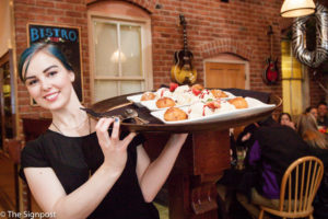 Waitress Amanda Coy brings out a tray of Bistro 258's signature dessert, Fuzzy Peaches. (Christina Huerta / The Signpost)