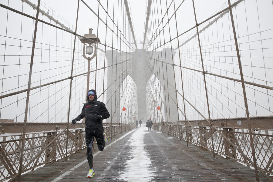 A man runs across the Brooklyn Bridge in New York on Saturday, Jan. 23, 2016, during a weekend snow storm blanketing the East Coast in snow. (Source: Tribune News Service)