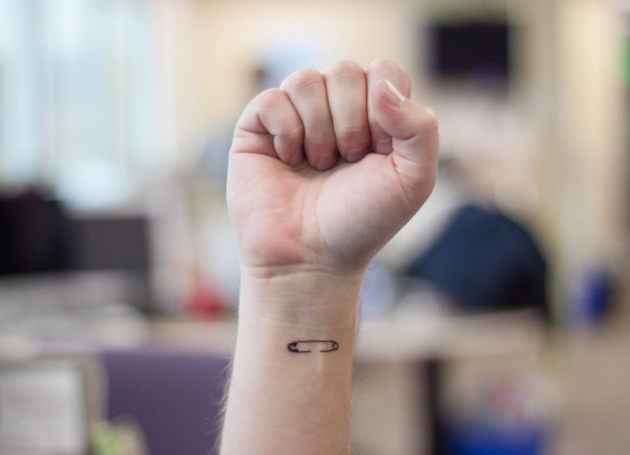 Ben Bigelow, a copy editor for The Signpost, shows his safety pin tattoo as a permanent mark that he will not stand for bigotry and hatred. (Photo Illustration by Emily Crooks / The Signpost)