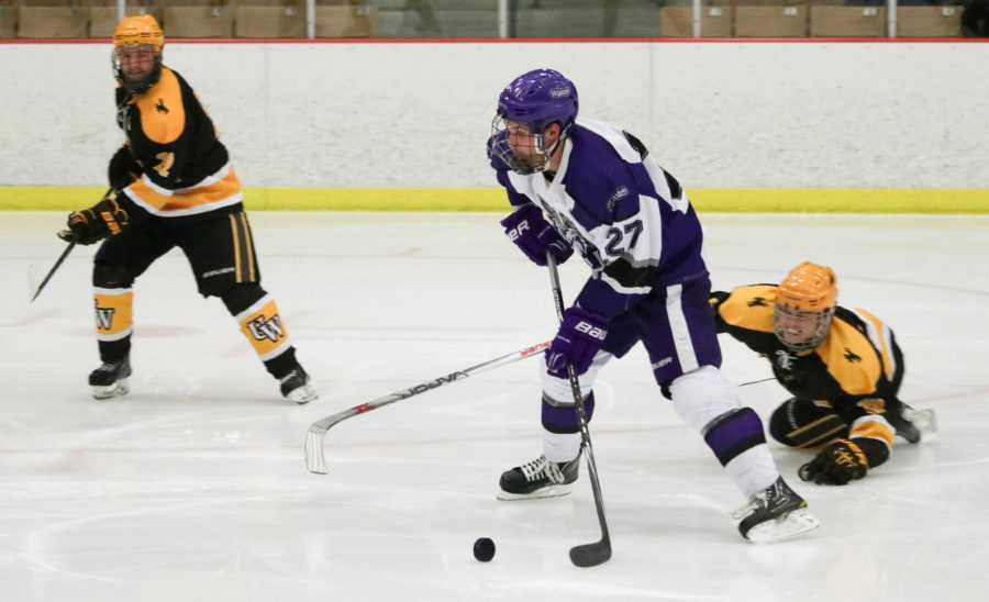 Forward Dax Hobbs takes the puck away from a fallen Wyoming player on Nov. 3. (Abby Van Ess / The Signpost)