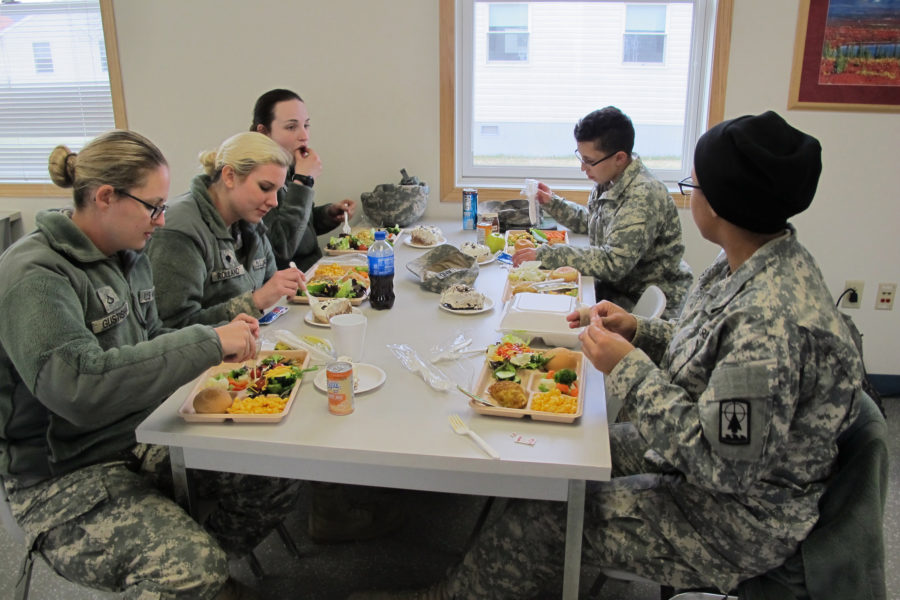 Pfc. Kendel Gustisha, front left, and Spc. Jocelyn Kopac, front right, dig in to hot food served up by the Wisconsin Army National Guard Headquarters Co. after spending the day out in the cold. Local businesses are offering a free meal to veterans on Nov. 11. (Source: Tribune News Service)