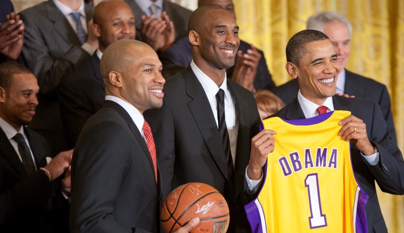 President Barack Obama holds a personalized team jersey presented to him by Los Angeles Lakers guards Kobe Bryant, center, and Derek Fisher, left, during a ceremony in the East Room of the White House honoring the 2009 NBA basketball champions, Jan. 25, 2010. (Source: Lawrence Jackson / Wikimedia Commons)