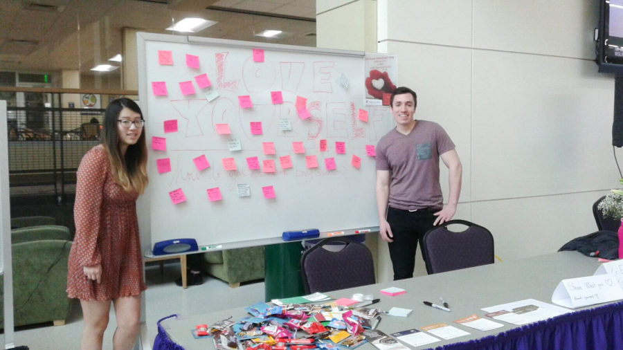 Cheyenne Liang, intern for Weber State Universitys counseling center, and Daniel Gibbons, Stop the Hate chair, stand beside the board of self-love sticky notes in the Shepherd Union. (Juliana Palacio / The Signpost)