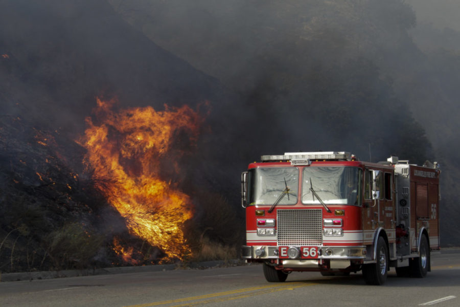 A fire truck passes by burning brush along La Tuna Canyon Road, closed to traffic, in the Verdugo Mountains north of Los Angeles on Saturday, Sept. 2, 2017. (Irfan Khan/Los Angeles Times/TNS)