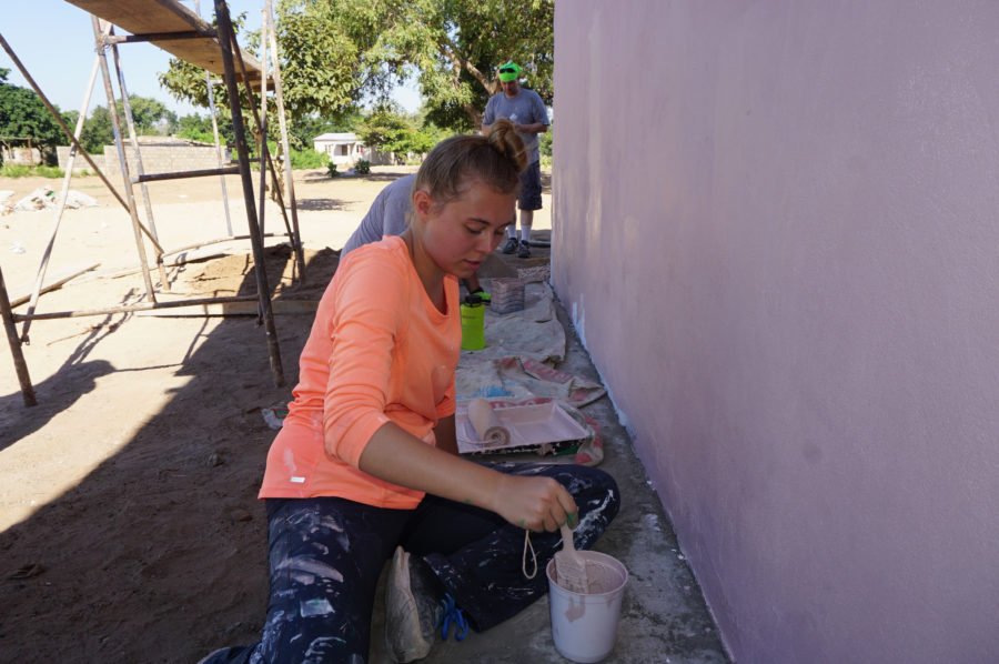 Hailey Simmons, center, painting the wall of one of the buildings her group erected in Mahubo, Mozambique. (CCEL / Weber State)