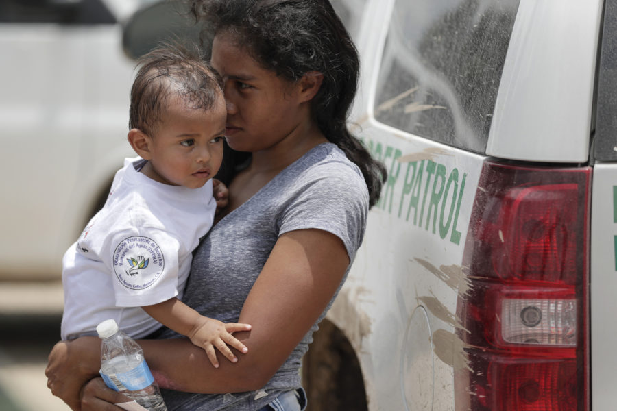A woman from Hunduras carries her baby, 14 mos., after surrendering to border patrol agents on June 25, 2018 near Granjeno, Texas.  (Robert Gauthier/Los Angeles Times/TNS)