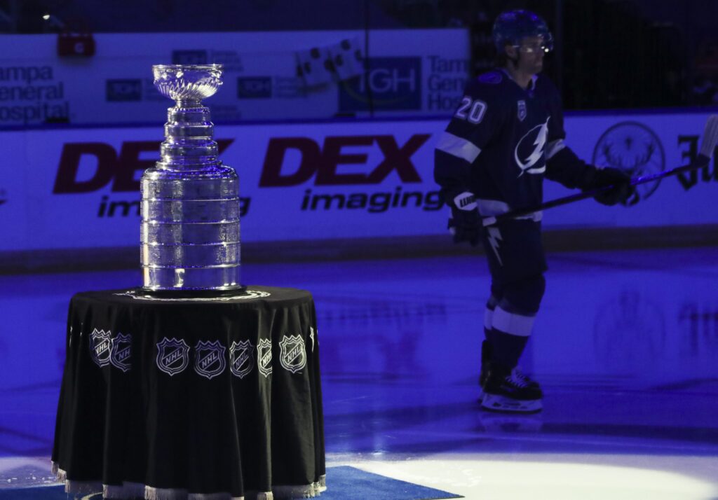 Lightning center Blake Coleman skates by the Stanley Cup as players gather at center ice before the game starts.