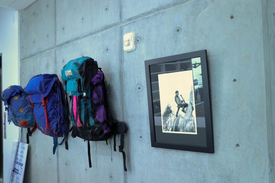 Backpacks hang on a wall next to picture of a rock climber for new Outdoor Program Recreation Center. (Katherine Berghout/ The Signpost)