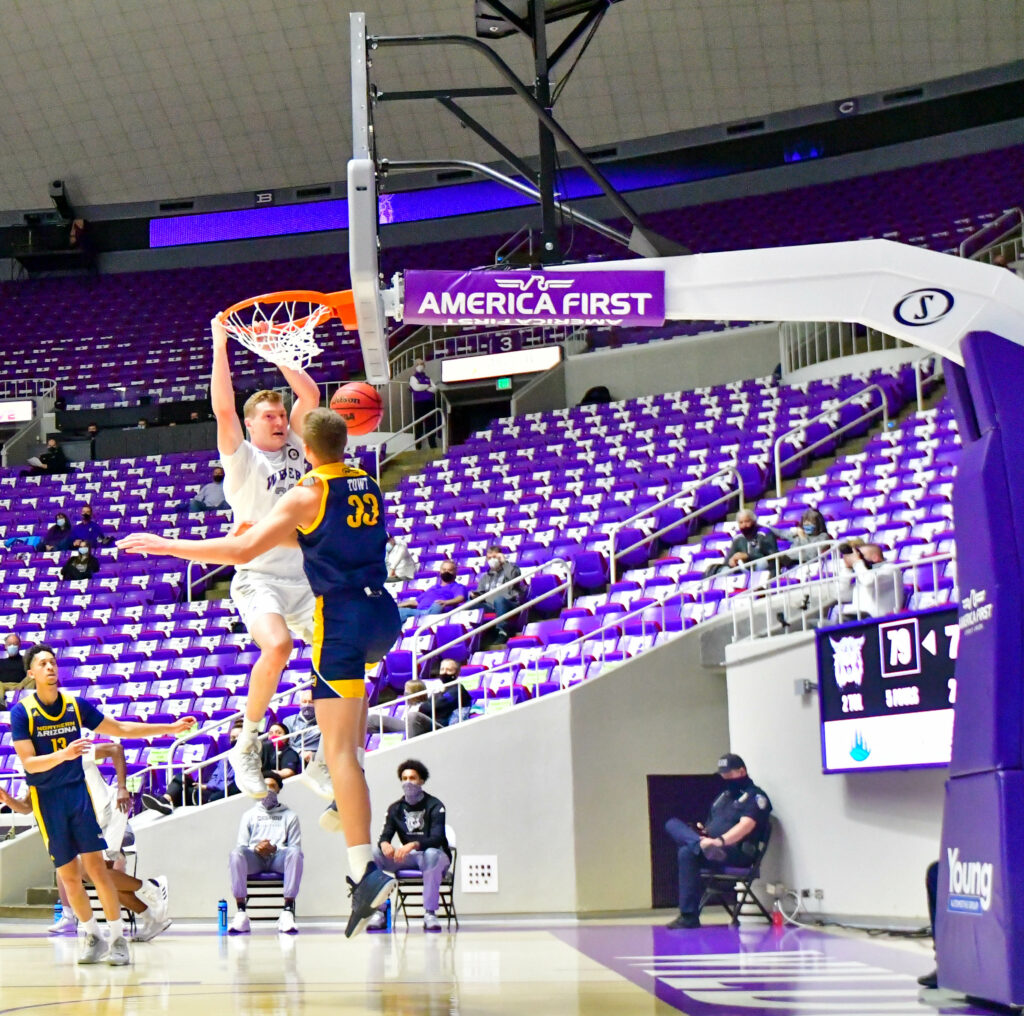 Weber State's Cody Carlson, number 34, slam dunks the ball with Northern Arizona's Towt, number 33, there to rebound.  (Nikki Dorber / The Signpost)