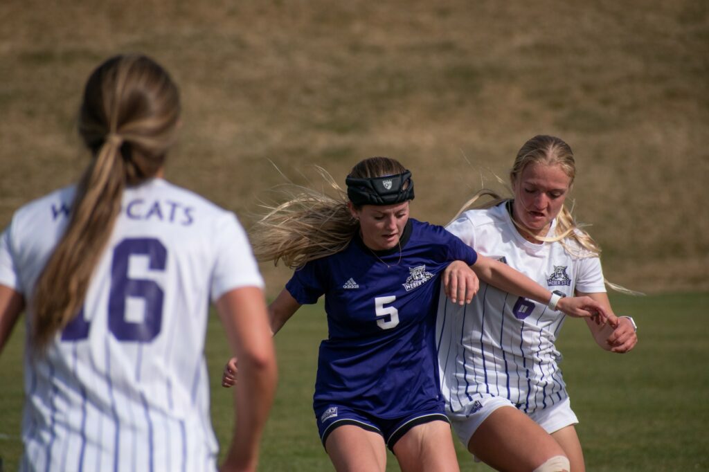 Two players fight for the ball, shoulder to shoulder ,on the Weber State soccer field on March 19. (Paige McKinnon/The Signpost)