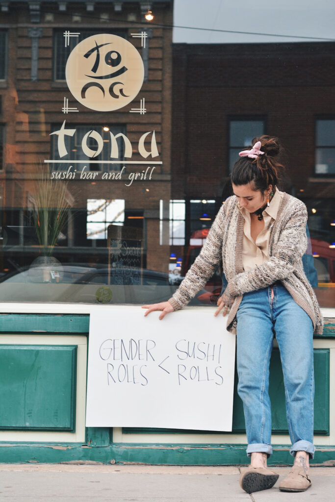 Mak holds a sign reading "gender roles < sushi rolls," Sunday, Mar. 14, 2021, in Ogden, Utah. (Brooklynn Kilgore/The Signpost)