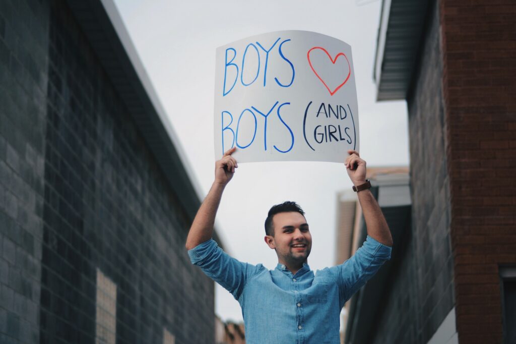 Chandler Reevs proudly displays a poster that reads "BOYS ♡ BOYS (AND GIRLS)," Sunday, Mar. 14, 2021, in Logan, Utah. (Brooklynn Kilgore/ The Signpost)