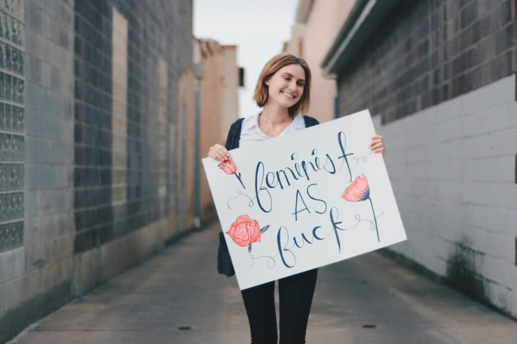 Madi Brenchley carries a sign that says "feminist as fuck," Sunday, Mar. 14, 2021, in Logan, Utah. (Brooklynn Kilgore/ The Signpost)