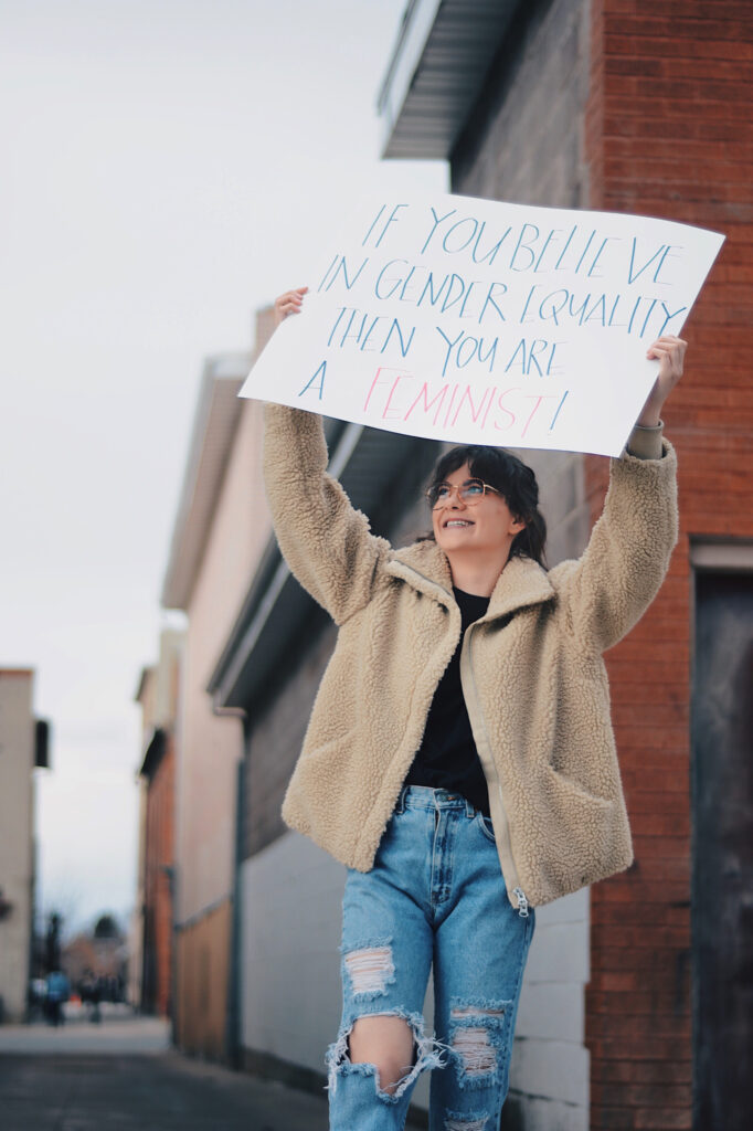 Emily Daines grasps a sign reading "If you believe in gender equality then you are a feminist!," Sunday, Mar. 14, 2021, in Logan, Utah. (Brooklynn Kilgore/ The Signpost)
