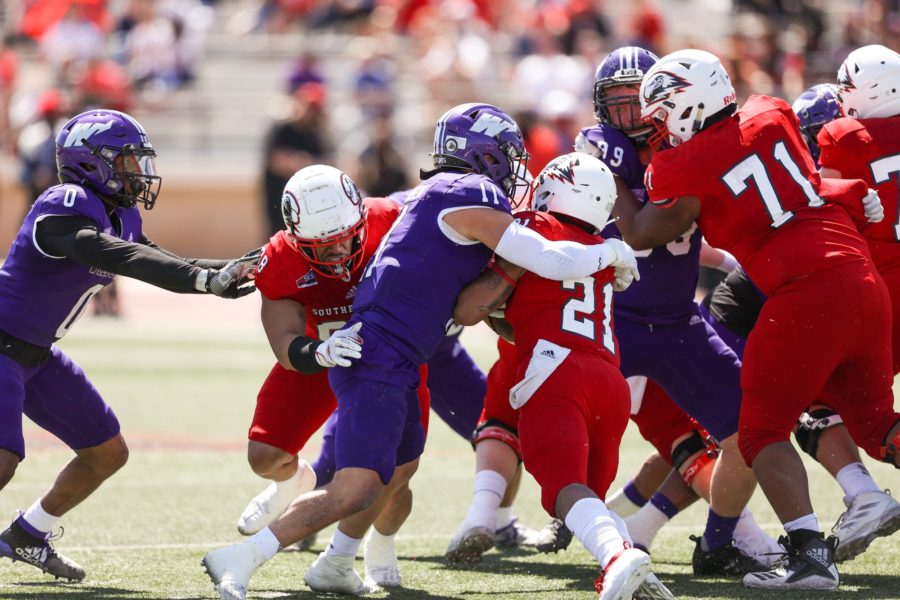 Wildcat senior linebacker Conner Mortensen, 11, wraps up SUU running back Jay Green Jr, 21, and Wildcat safety Desmond Williams, 0,  looks to assist him at Eccles Coliseum in Cedar City on April 3. Photo credit: Robert Casey & Weber State Athletics