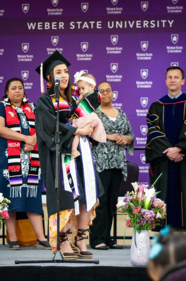 A Latinx graduate walks across the stage with her child, a memorable moment during a past ceremony. Photo credit: LatinX Grad Ceremony