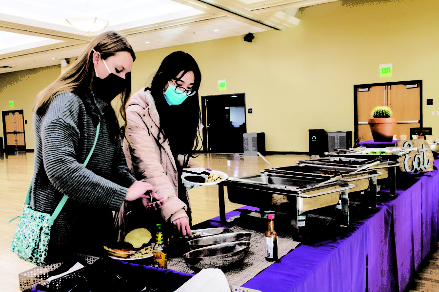 A variety of food was available to the students who attended Eddies BBQ, pictured from left to right is Madison Dasturp and Riley Cao getting a plate full of their own food. (Kennedy Robins/ The Signpost) Photo credit: Kennedy Robins