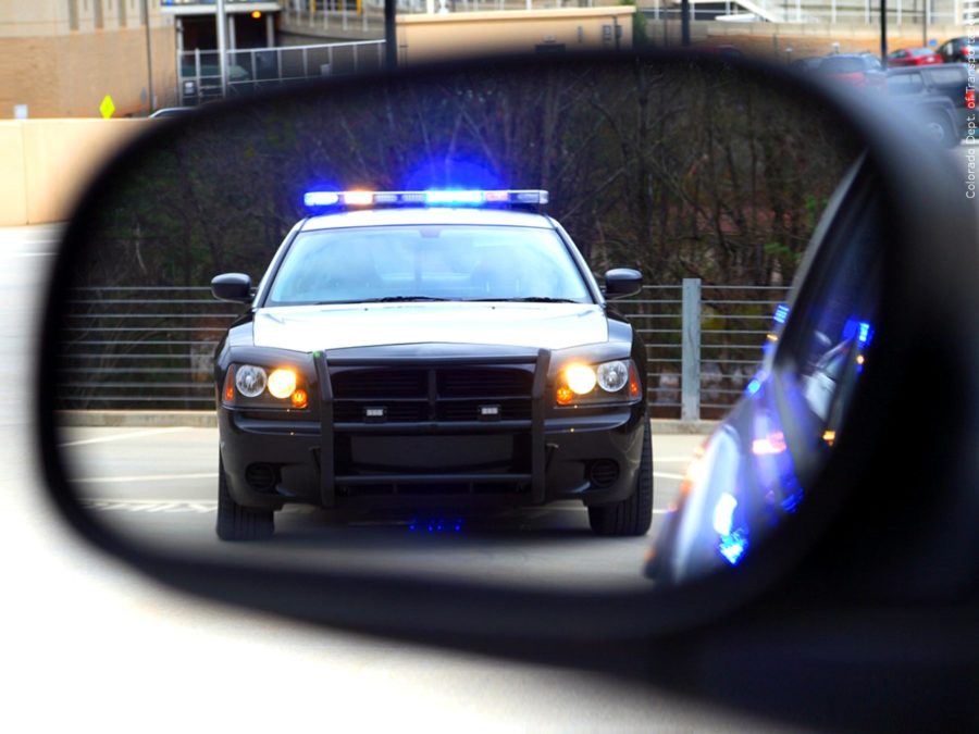 A police car is shown in the reflection of a car mirror. Photo credit: MGN