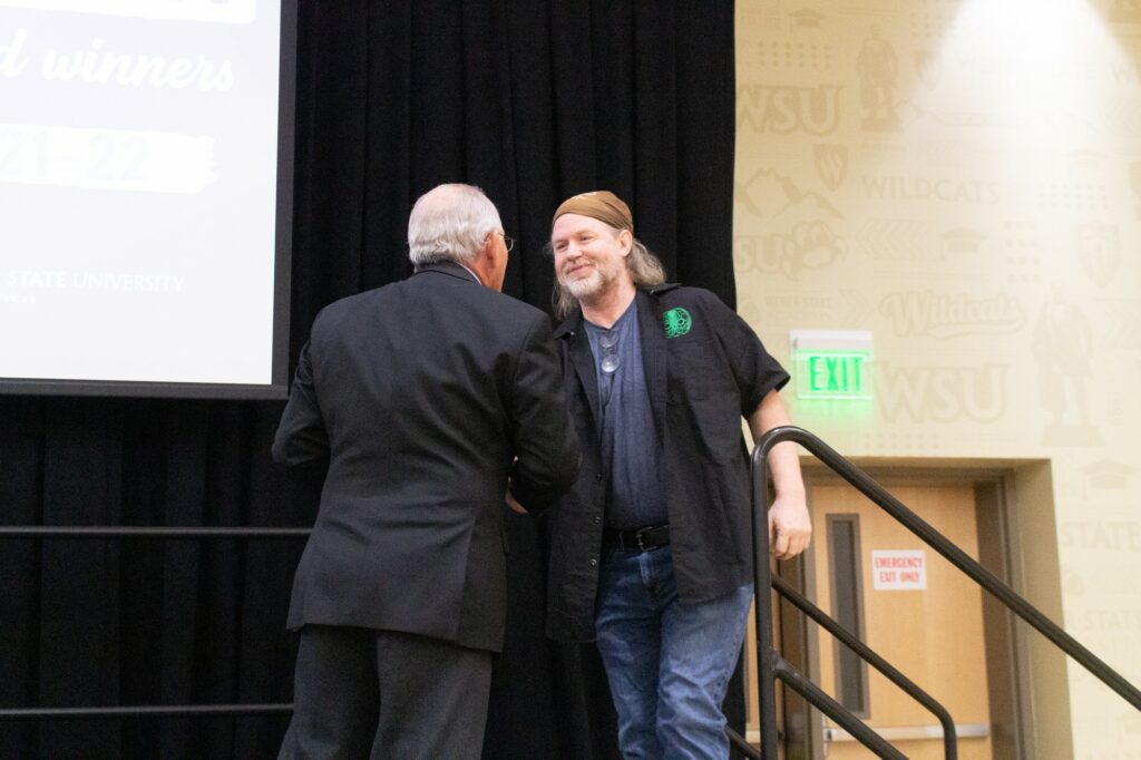 Winn Stanger shaking career champion Patrick Murphy's hand before giving him his award. (Kennedy Robins/ The Signpost)