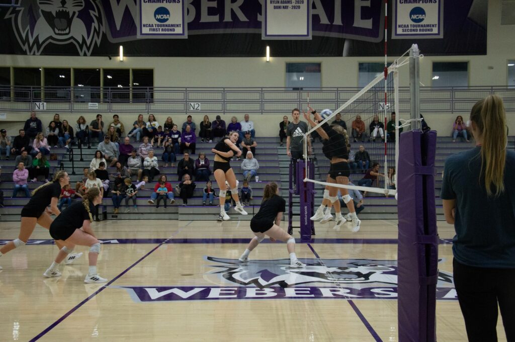 Dani Nay spikes the ball over the net as UVU players attempt to block. (Summer Muster/The Signpost)