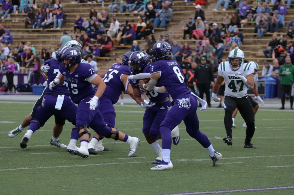 Wildcat's Creyton Cooper (#8) hands off the ball against the Viking's defense. (Bella Torres / The Signpost)