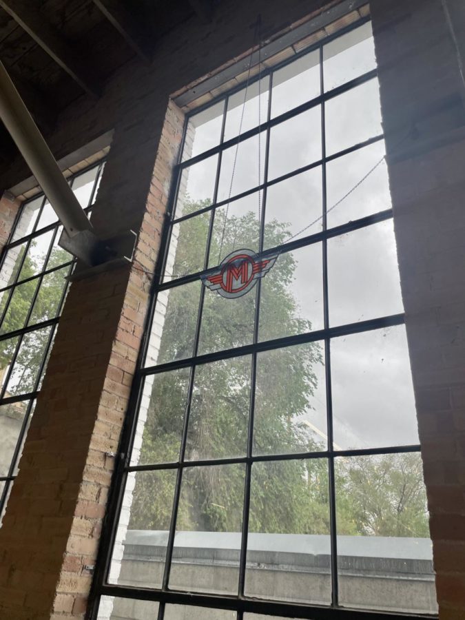 A stained glass version of the Monarchs logo hangs in front of a large window.
