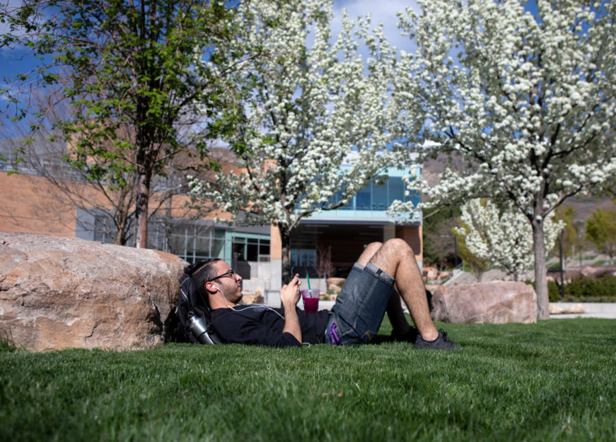 A student relaxes on campus between classes taken on April 23, 2019.