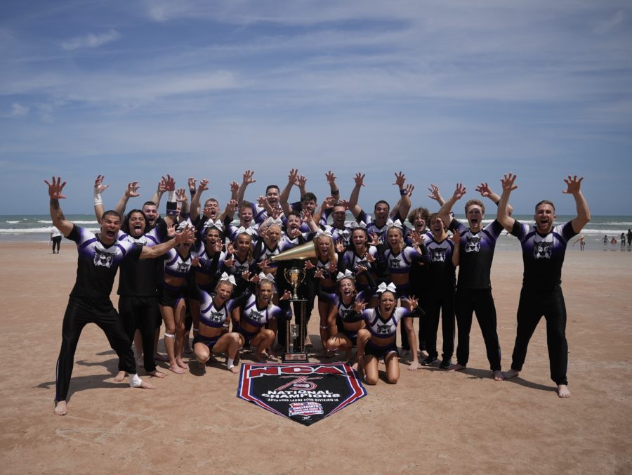 Wildcats take photo on the beach after victory in the Advanced Large Co-Ed Division I Grand National Championship