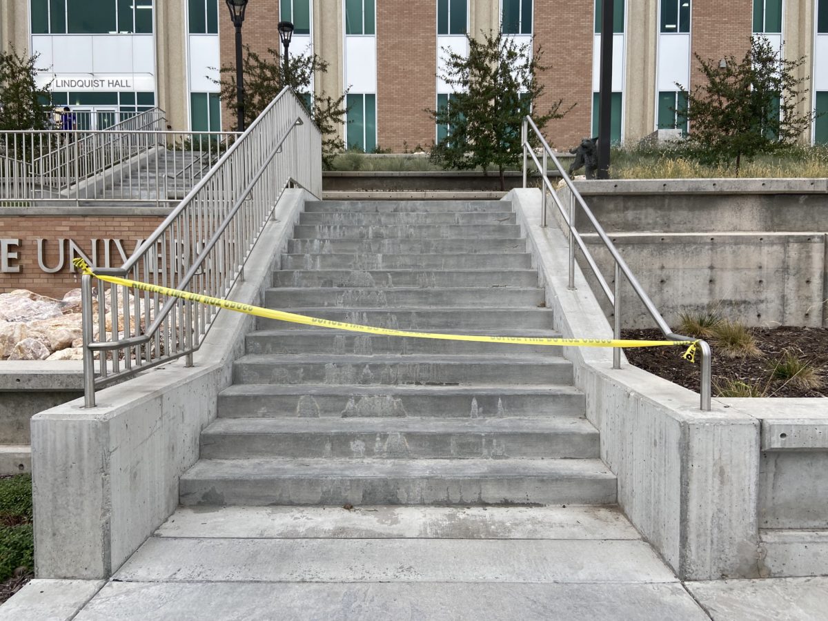 Construction tape restricting access to a Lindquist Hall staircase located in front of the A1 parking lot.