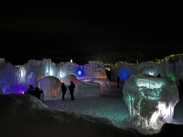 Night view of the entrance of the colorful Ice Castle on a full moon.