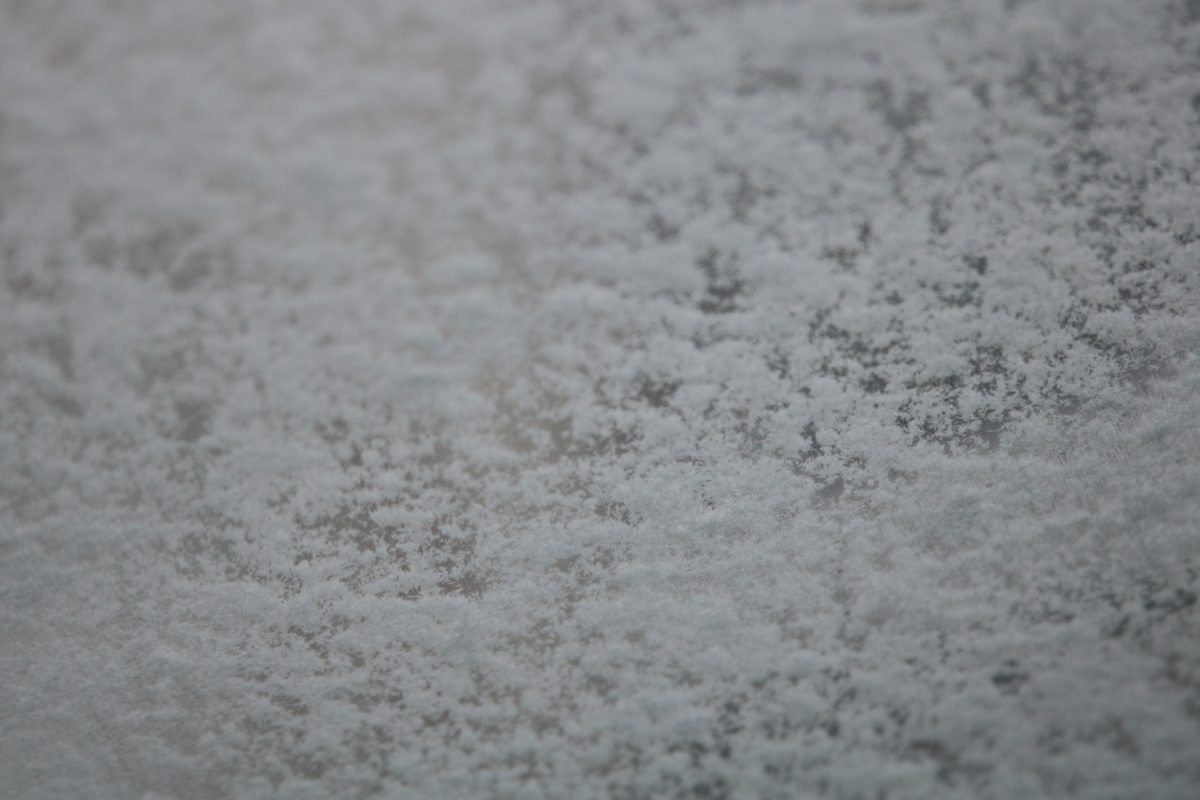 Snowflakes falling and coating the windshield of a car.