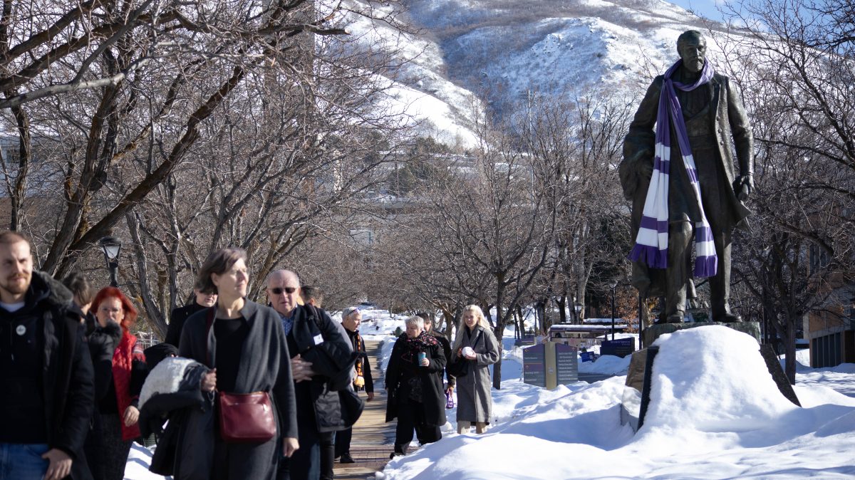 Students walk past the statue of Louis Moench that stands outside of Lindquist Hall, draped in a Weber State scarf.