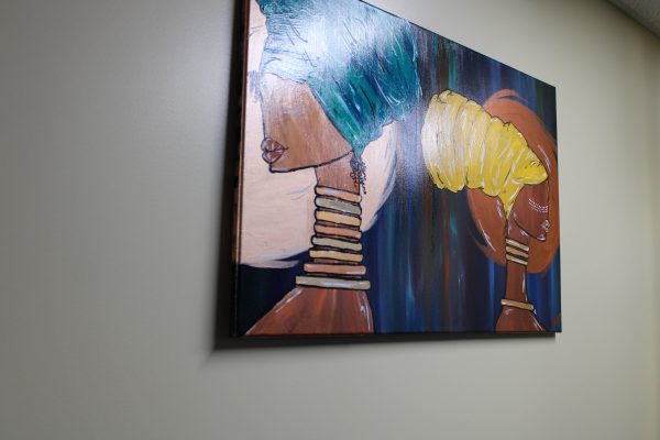 A painting hanging up in the Black Cultural Center depicting two women wearing Afro-heritage attire. 