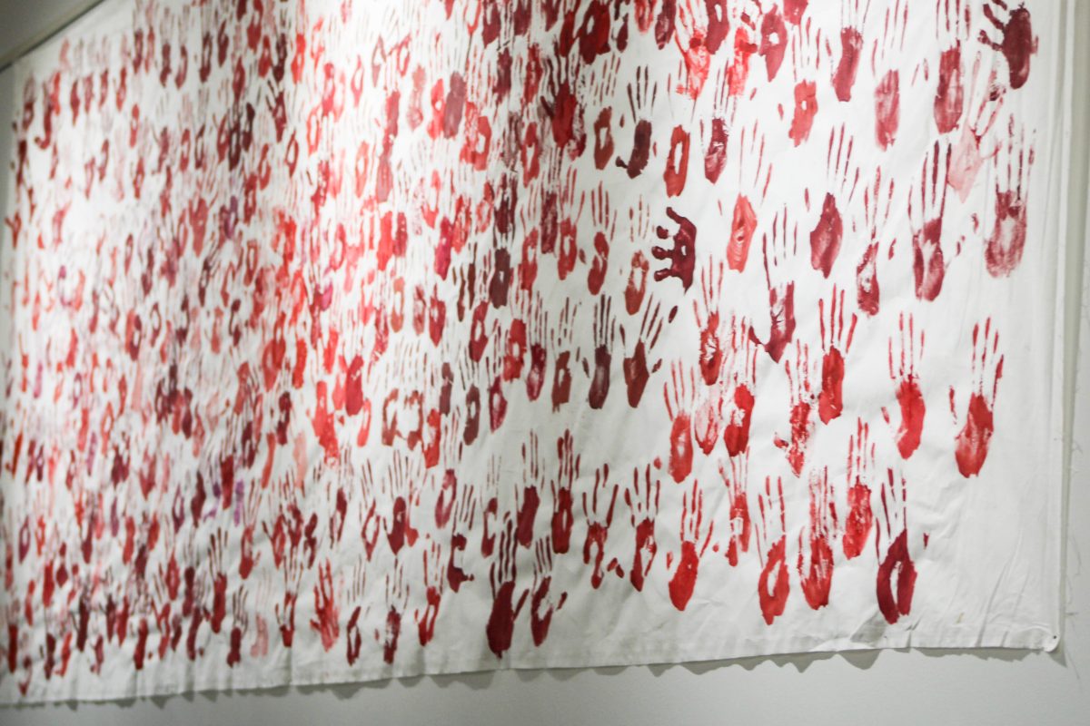 A poster covered in red-painted handprints of students, hangs in the hallway between Shepard Union and Student Service, to bring awareness of MMIW in Utah and the Weber State campus.