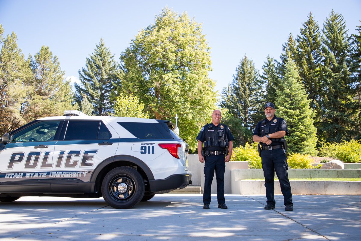Brad Hansen, left, and Shane Nebeker stand in front of a USU police car.