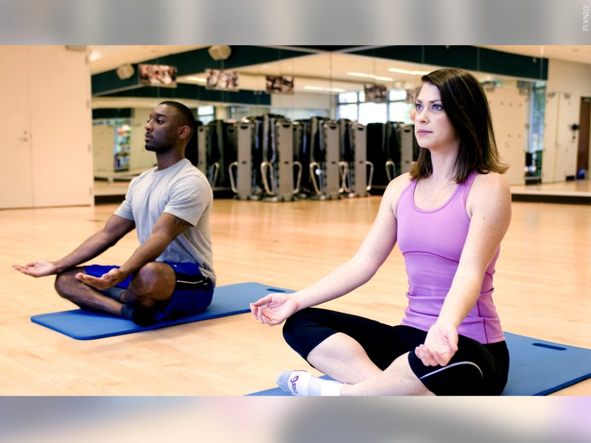 Two people meditating in Lotus pose during a yoga class.