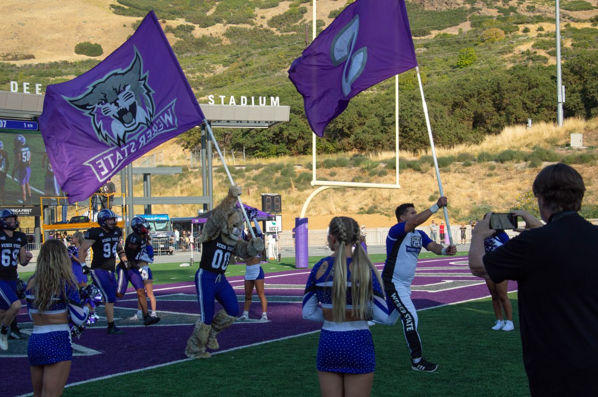 Weber State cheerleaders leading the WSU football team to the field.