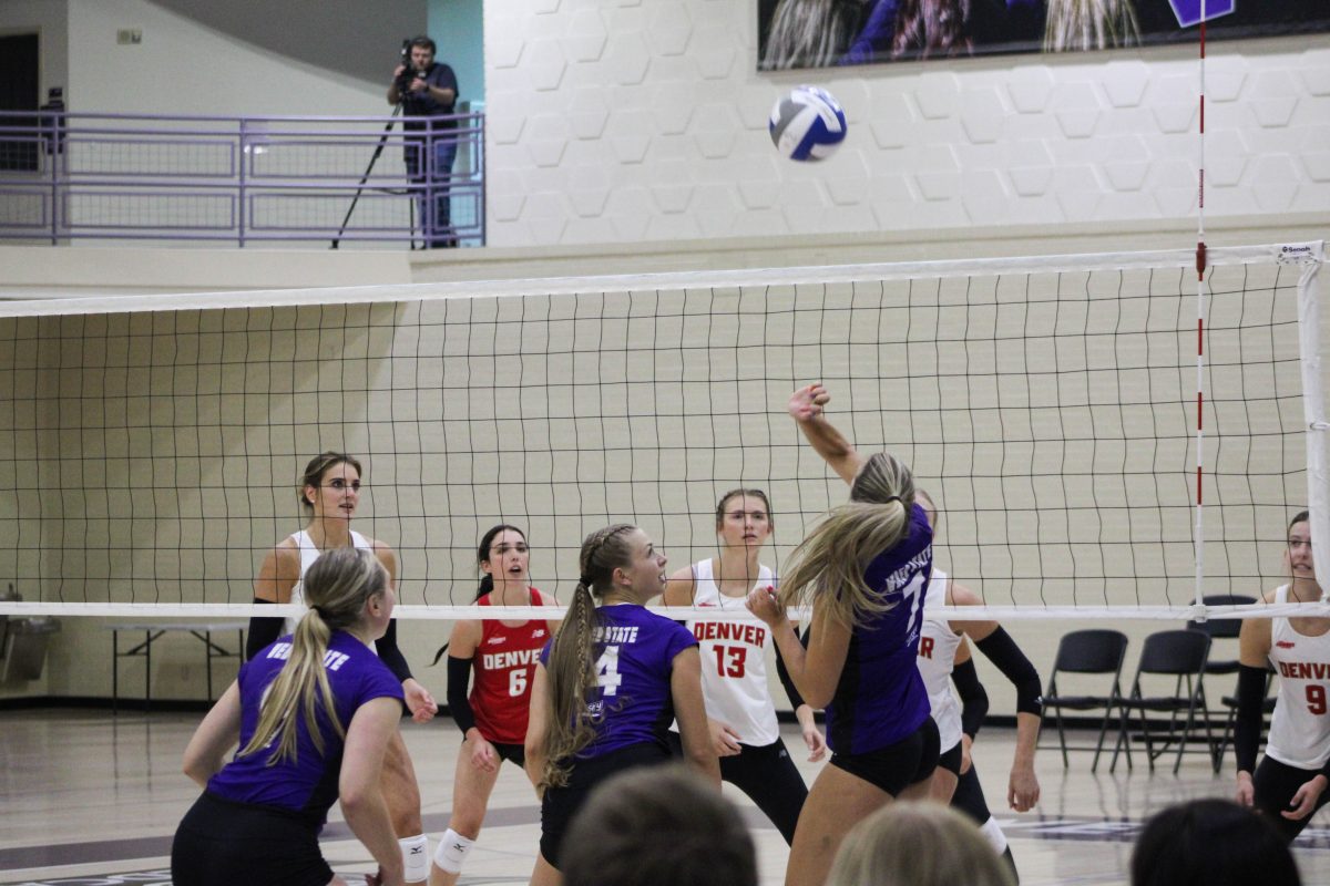 Opposite Baylee Bodily (#7) preparing to block the ball from the Denver Volleyball team.