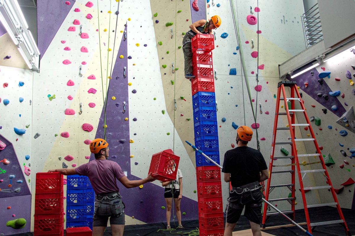 Everyone in the team is working together to lift the boxes up and stack them up high.