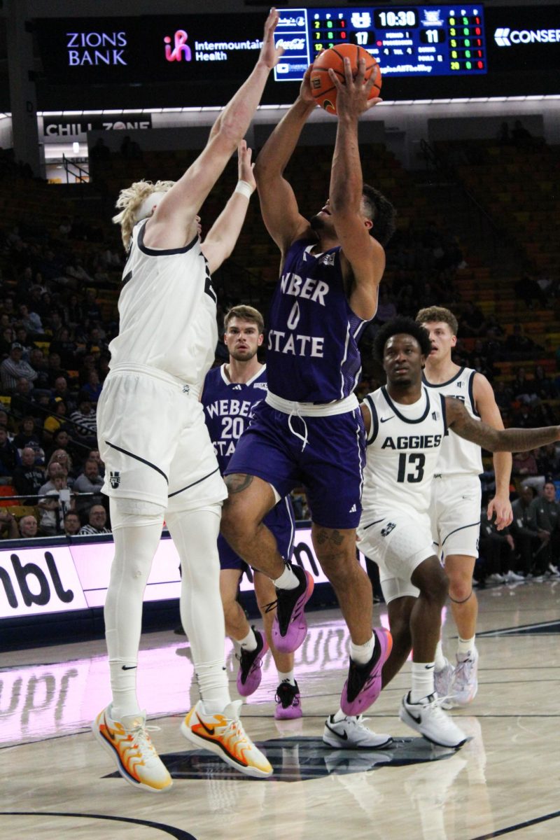 Blaise Threatt (0), driving to the basket with Utah State contesting.