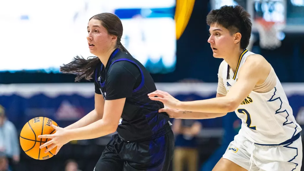 Weber State University keeping the ball away from Northern Arizona player.// La Universidad de Weber State manteniendo la pelota lejos de una jugadora de Arizona del Norte.//