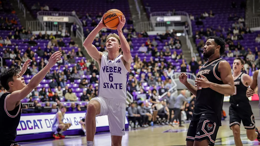 Weber State Guard Trevor Hennig (#6), jumping to make a hoop against Idaho State Bengals.// El guardia base de Weber State Trevor Hennig (#6) saltando para hacer una cesta en contra de los Bengals de Idaho State.