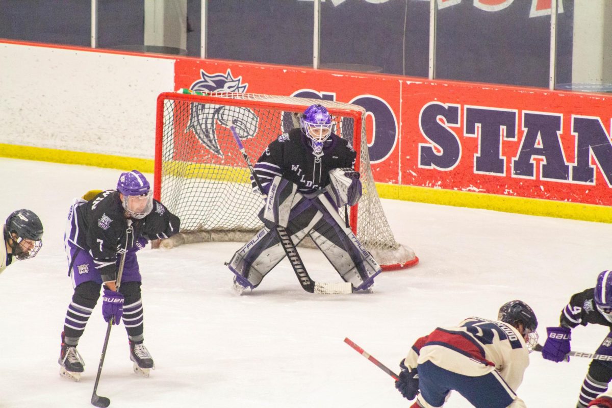 Defensemen Kody Goodwin (#7) and goalie Robbie Brennan (#79) are preparing for Metro State University to hit the hockey puck in their direction.