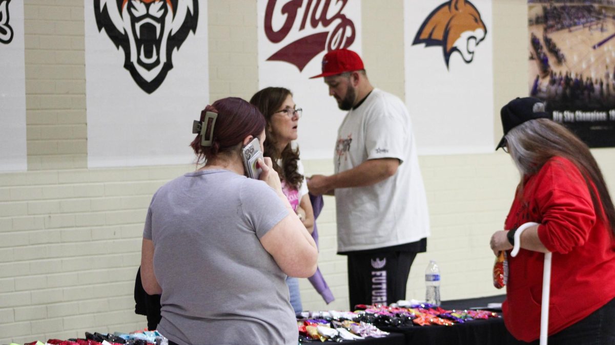 A vendor table set up at the Future Flyers event sells cheerleading bows and other cheerleading related items.// La mesa de los vendedores siendo armada en el evento de Future Flyers vende tazones y otros objectos relacionados con porrismo.