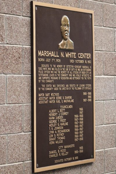 A plaque inside of the Marshall White Center, dedicating the building in honor of his memory.// Una placa dentro del centro Marshall White, dedicando el edificio en honor a su memoria.